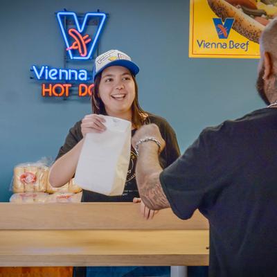 A server handing over a paper bag to a customer at a counter.