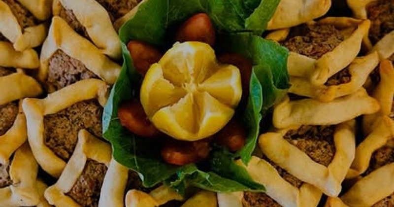 Lebanese meat pastries arranged with lemon and greens