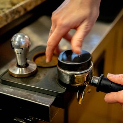 Hands operating the coffee machine.
