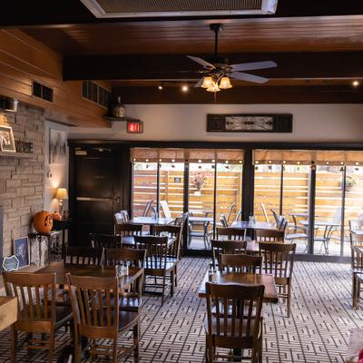 Dining room with fireplace, wooden beams on the ceiling, and large windows.