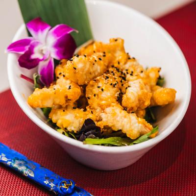 Hot and crispy shrimp topped with sesame seeds and garnished with a flower.