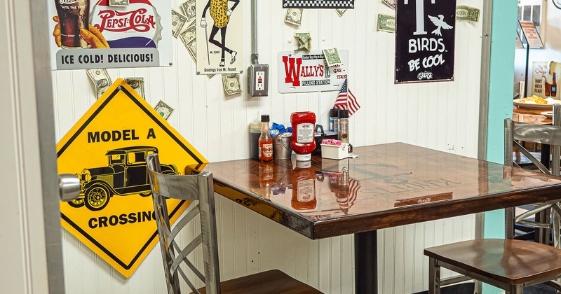 Interior dining area, table for two guests by the wall decorated with vintage signs