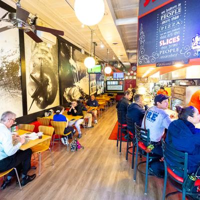 Patrons sit at tables and a counter inside the restaurant.