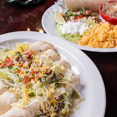 Enchiladas with green sauce, tomato salsa, and shredded cheese.