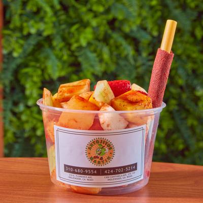 Fruit cup with chili powder and a tamarind candy stick.