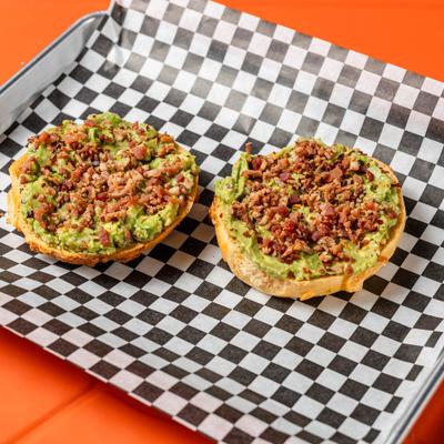 Toasted bagel halves topped with mashed avocado and crispy bacon crumbles.