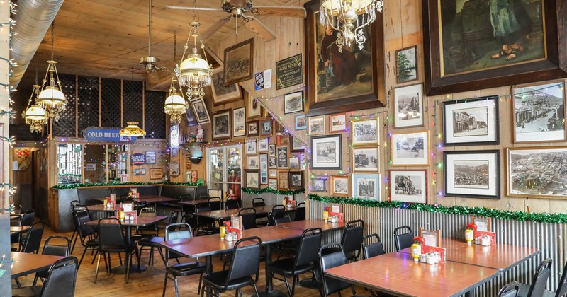 Interior seating space with tables and a booth, chandeliers and wall decoration