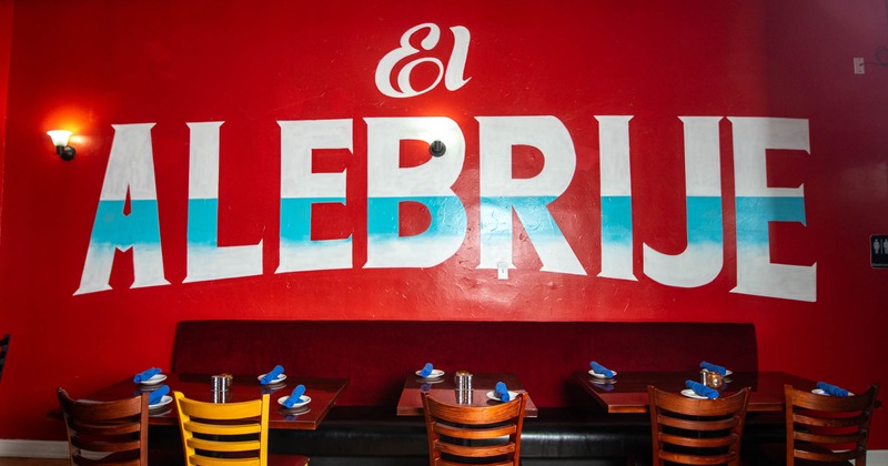 Interior, banquette seating and tables with chairs, restaurant's logo on the wall