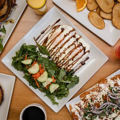 Avocado toast topped with fried eggs and balsamic drizzle, served with a side salad.