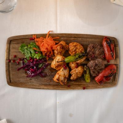 Turkish mixed grill platter with chicken, beef, roasted peppers, and a salad garnish.
