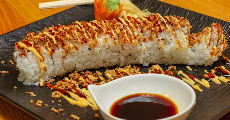 Sushi rolls topped with spicy sauce and crunch