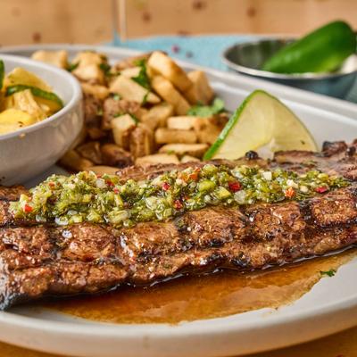 Grilled skirt steak topped with chimichurri sauce, served with roasted potatoes.