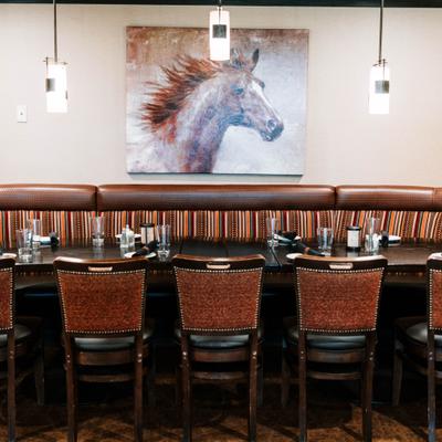 Restaurant banquette seating with an upholstered bench and a painting of a horse.
