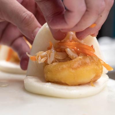 Hands assemble a bao slider, close up.