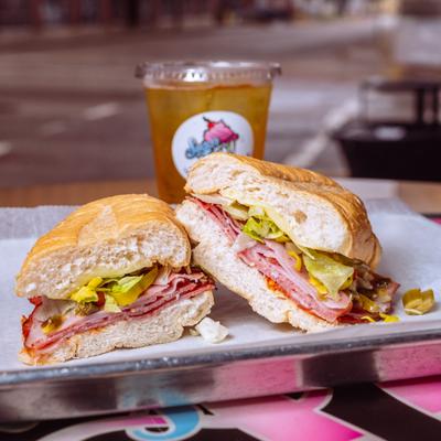 Italian sandwich on tray with iced drink.