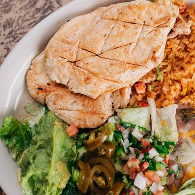 Grilled chicken with rice, pico de gallo, and jalapenos on a plate.
