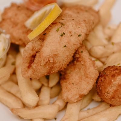Fried fish with  fries, hushpuppy and a slice of lemon, close up.