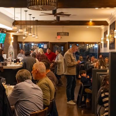Guests seated at the bar and booths in a busy restaurant.