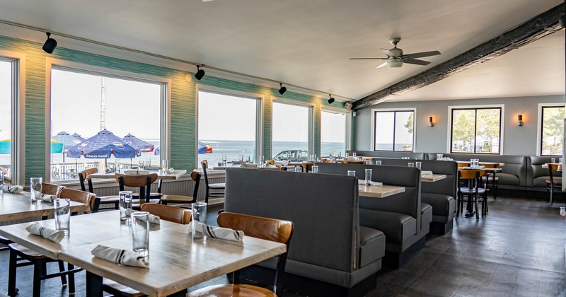 Interior of a bright restaurant with views of water through large windows