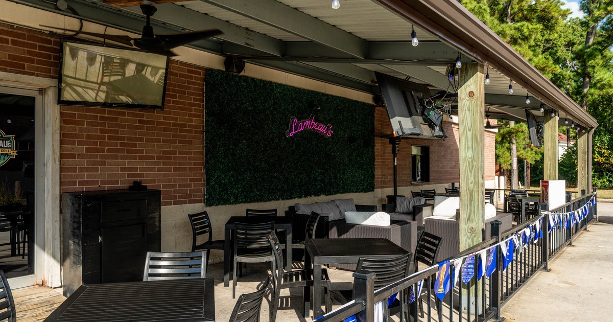 Covered restaurant patio with tables chairs and televisions