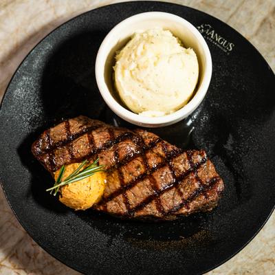 Angus steak served with a side of mashed potatoes.