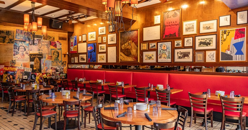 Interior of a restaurant featuring wooden tables and chairs, red banquette seating