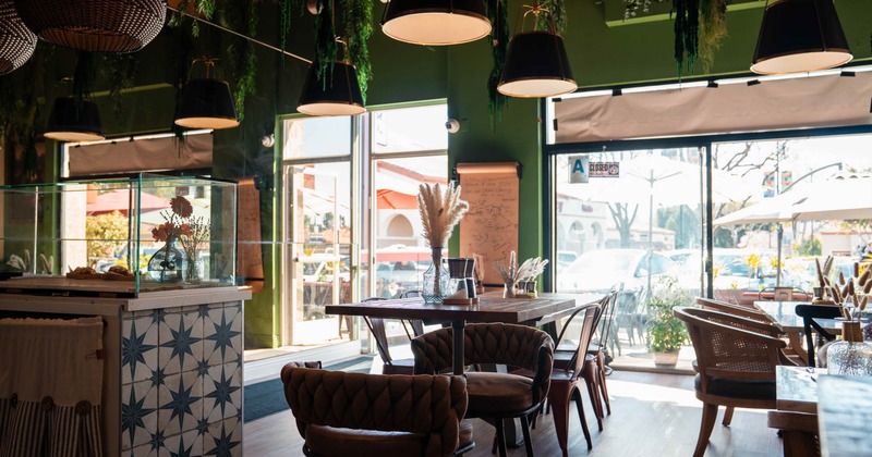 Trendy cafe interior with hanging black lamps, green walls, and wooden furniture