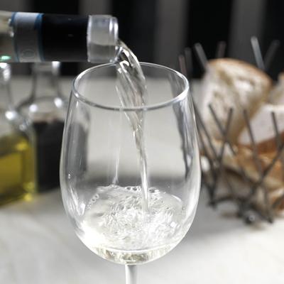 White Wine poured into a glass on a dining table.