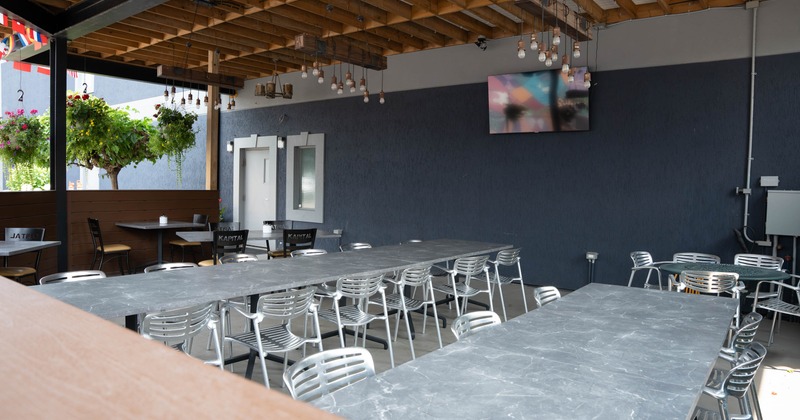 Exterior, covered seating area, long marble top tables for twelve, tables for four and two