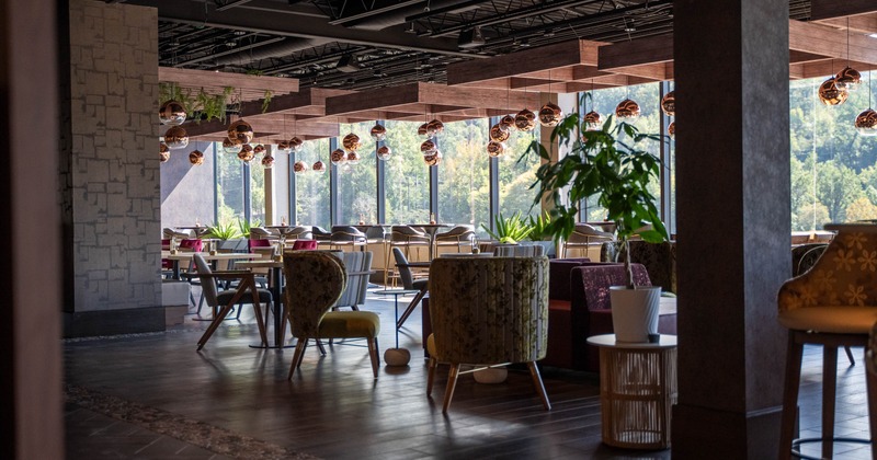 A modern, spacious restaurant with large windows, and various tables and chairs