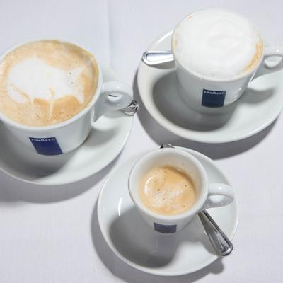 Three different types of coffee drinks, served in branded cups and saucers.