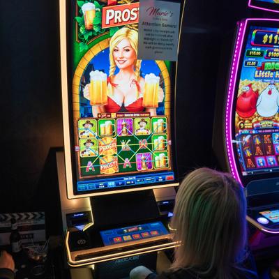 Person playing a slot machine with a colorful screen and game symbols.