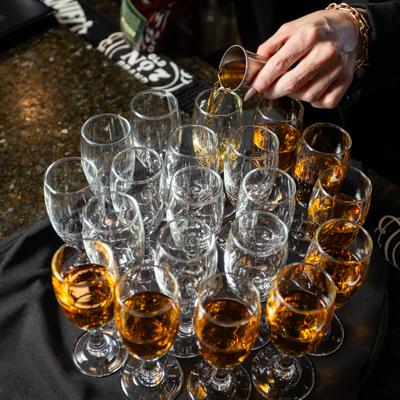 Server pouring drinks into neatly arranged tasting glasses.