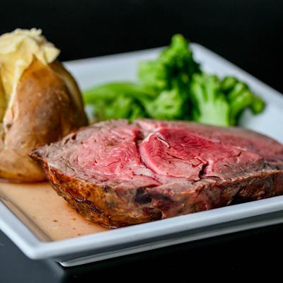 Prime Rib dinner plate with baked potato and broccoli.