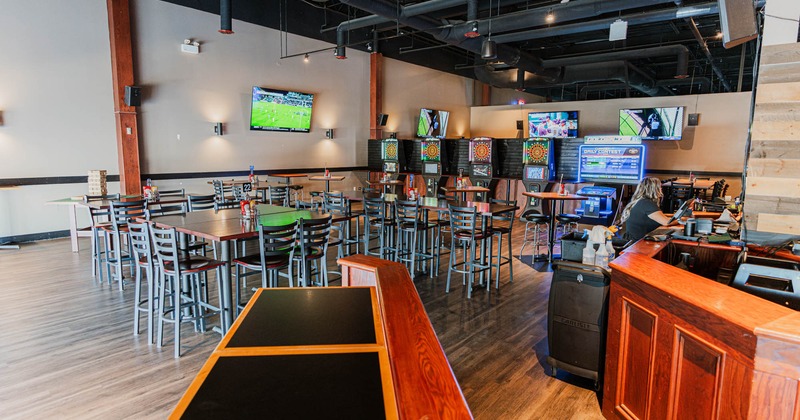 Interior, high seating area, electronic darts and games in the back, bar on the right