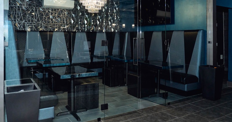 Interior with glass-enclosed booths, geometric patterned wall, and crystal chandelier
