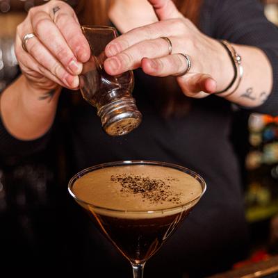 Bartender sprinkling coffee grounds onto an Espresso Martini.