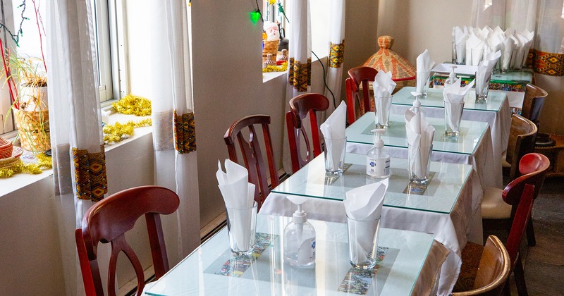 Dining tables set for two guests along the windows
