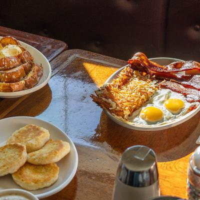 Breakfast plates with bacon, eggs, and hash browns, French toast, and English muffins.