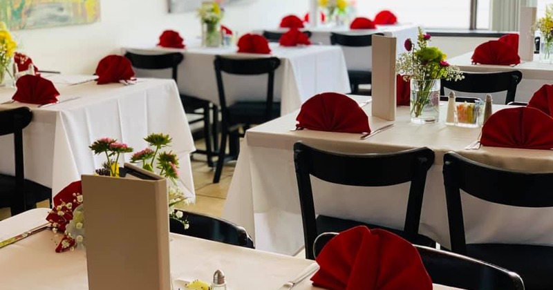 Interior, tables for four ready for guests, decoratevely folded red napkins