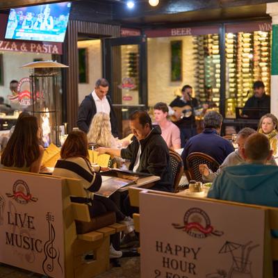 Outdoor dining area with seated guests and a live music performance.