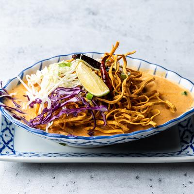 Curry noodle soup with crispy noodles, cabbage, and lime in a bowl.