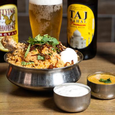Biryani chicken, cooked with Indian spices, served with cream and gravy, with beer on the side.