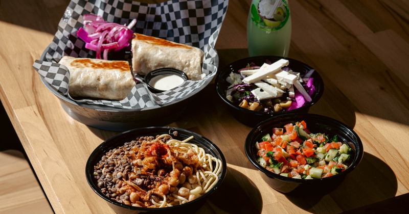 Shawarma with onions and sauce, pasta with legumes, feta salad, and diced cucumber-tomato salad