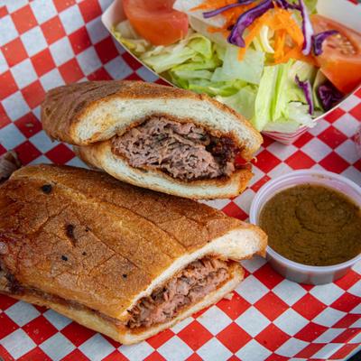 Tri-tip sandwich served with a side salad and dipping sauces.