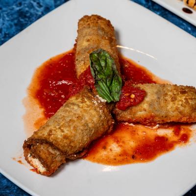 Eggplant Rollatini in tomato sauce garnished with basil.