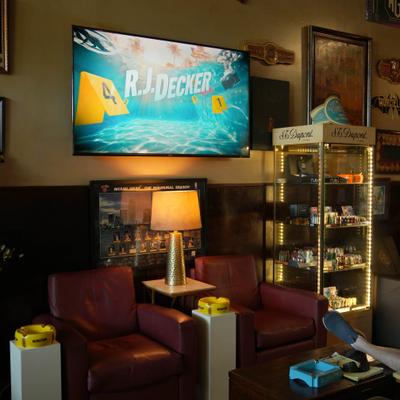 Lounge area featuring two armchairs, warm table lamp, glass display cabinet, and a TV.