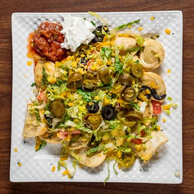 Perogy nachos topped with lettuce, cheese, pickled jalapenos, and olives.