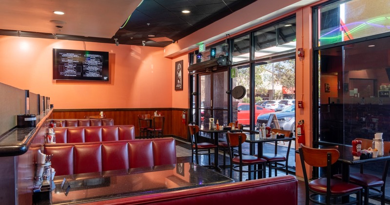 Interior of a diner with red booths, tables and large windows.