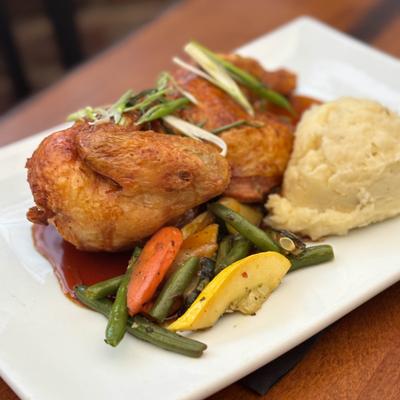 Half chicken served with mashed potatoes and seasonal vegetables.